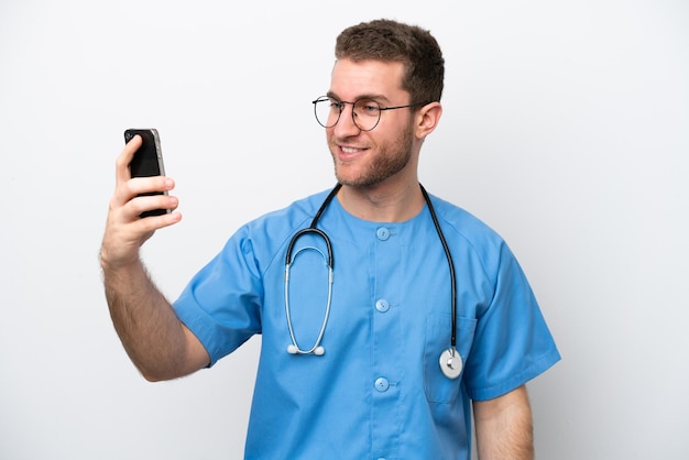Young surgeon doctor caucasian man isolated on white background making a selfie