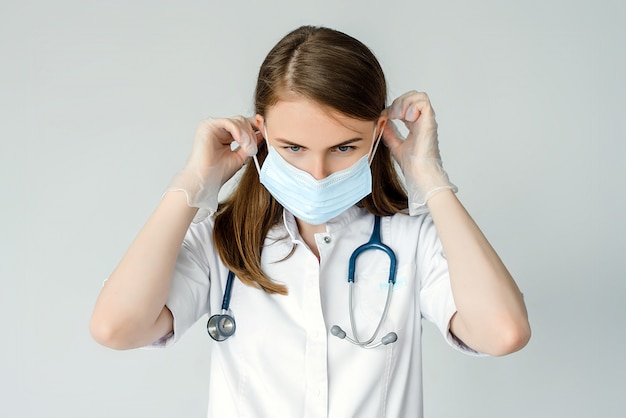 Young surgeon doctor in latex protective gloves wearing medical mask on face. Man professional medic in medical gloves put on protective face mask. Personal protection. Coronavirus COVID-19