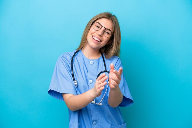 Young surgeon doctor woman isolated on blue background applauding after presentation in a conference