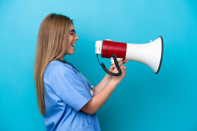 Young surgeon doctor woman isolated on blue background shouting through a megaphone