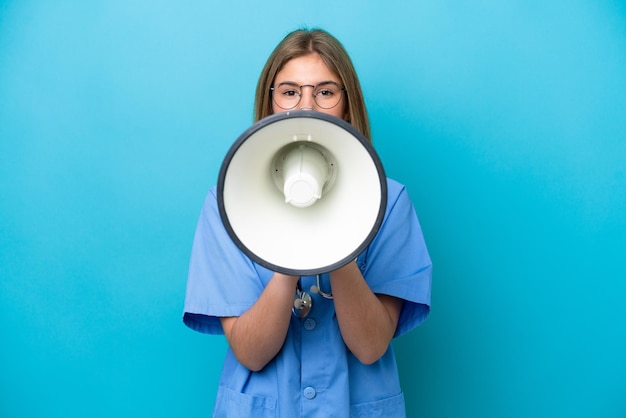 Photo young surgeon doctor woman isolated on blue background shouting through a megaphone