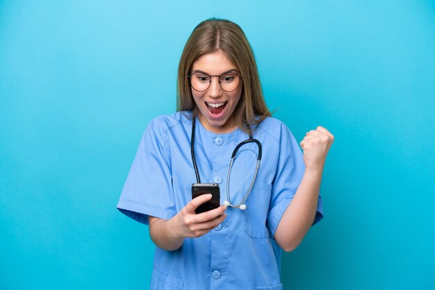 Young surgeon doctor woman isolated on blue background surprised and sending a message