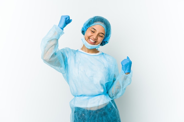 Young surgeon latin woman isolated on white wall celebrating a special day, jumps and raise arms with energy.