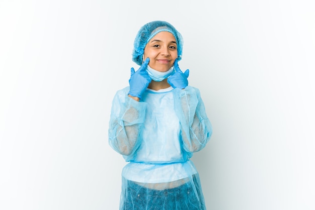 Young surgeon latin woman isolated on white wall doubting between two options.