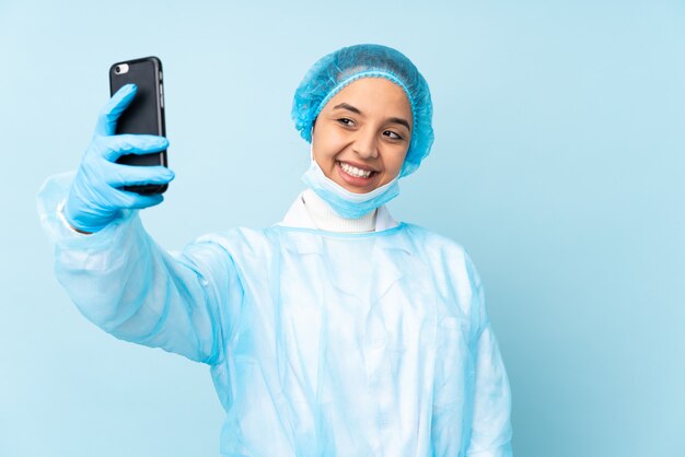 Donna giovane chirurgo in uniforme blu che fa un selfie