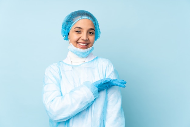 Молодая женщина хирурга в голубой форме представляя идею пока смотрящ усмехающся к