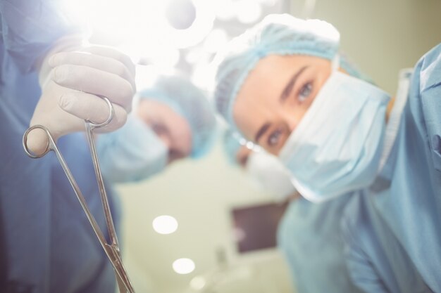 Young surgeons looking down at camera holding clamp