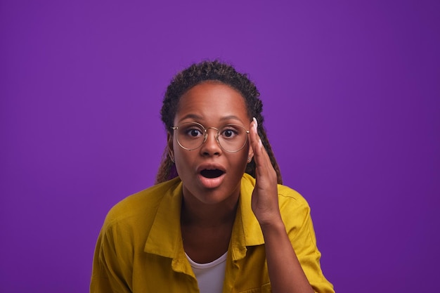 Young surprised african american woman opens mouth and looks at screen