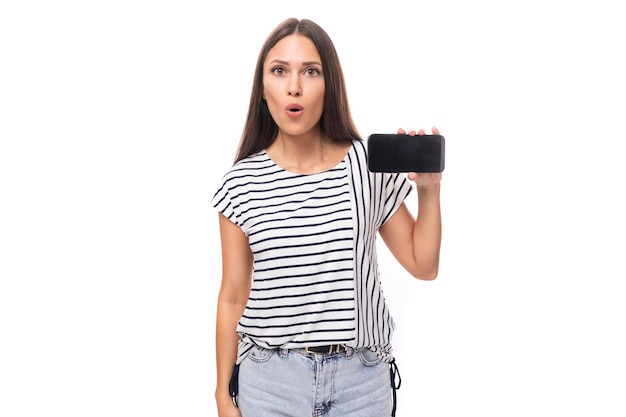 Young surprised brunette lady with straight hair in glasses dressed in a striped tshirt holding a