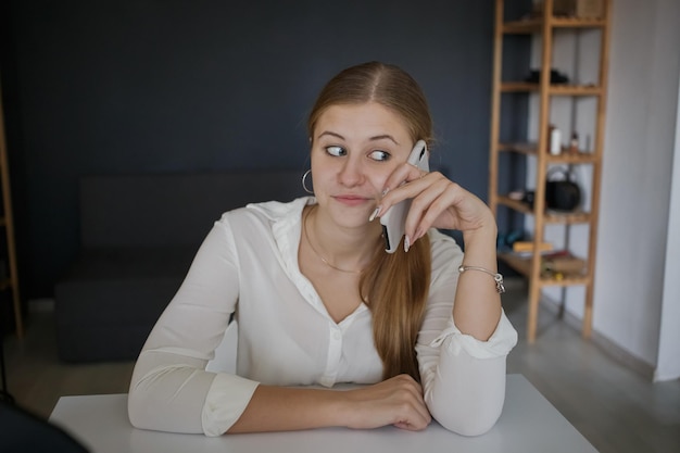 Young surprised successful business woman employee in white shirt talking on the phone