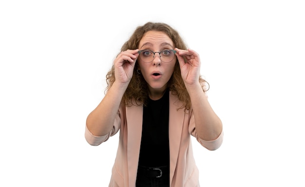 Young surprised woman holding her glasses with hands. She is wearing coral colored suit