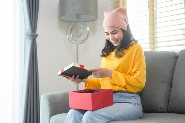 Young surprised woman opening a gift box in living room