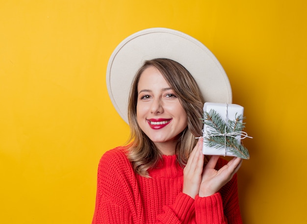 Donna sorpresa giovani in maglione rosso con il contenitore di regalo