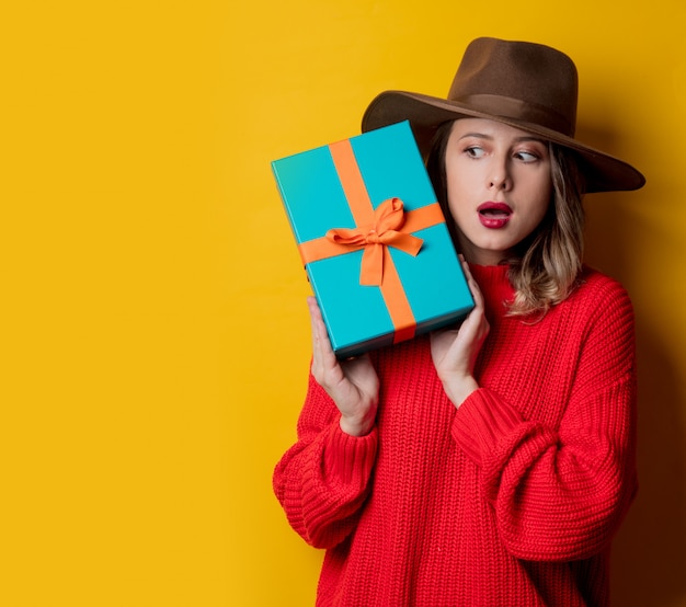 Young surprised woman in red sweater with gift box 