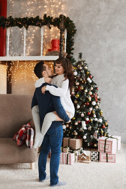 Young sweet couple posing in the living room interior decorated for christmas holidays