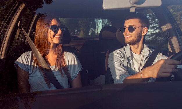 Young sweet couple talking during their car trip through sunset countryside