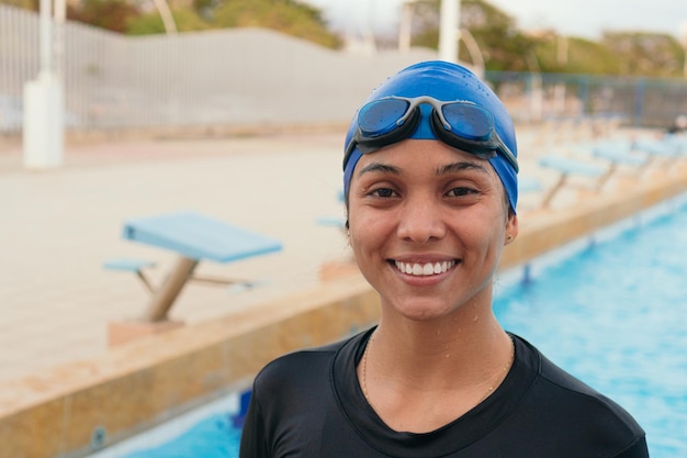 Young swimmer girl with swimming cap and goggles by the
pool