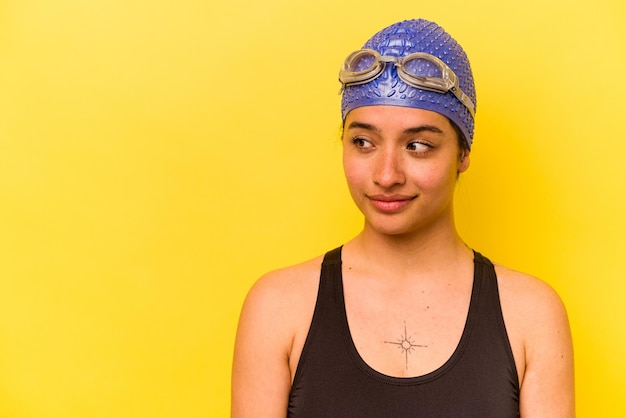 Young swimmer hispanic woman isolated on yellow background