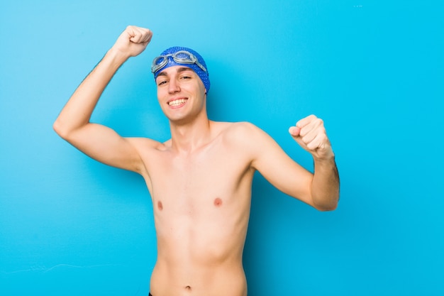 Young swimmer man celebrating a special day, jumps and raise arms with energy.