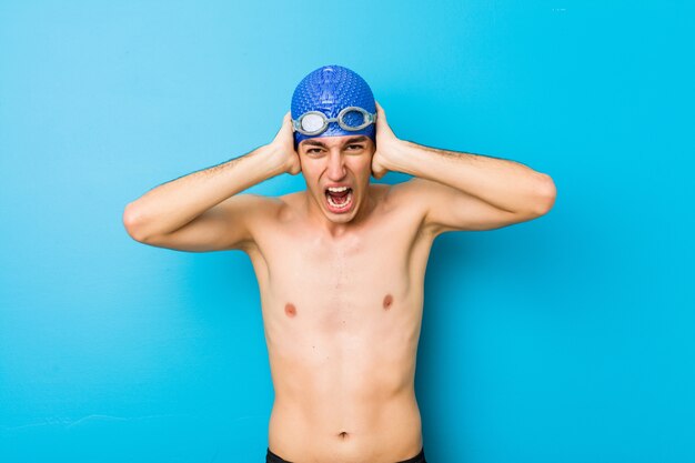 Young swimmer man covering ears with hands trying not to hear too loud sound.