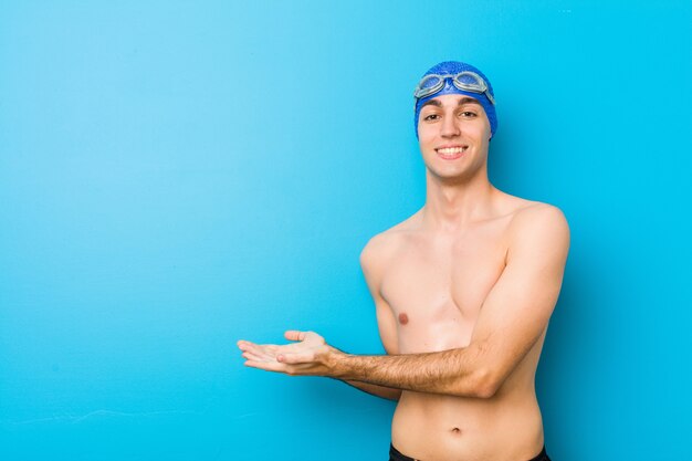 Young swimmer man holding a copy space on a palm.