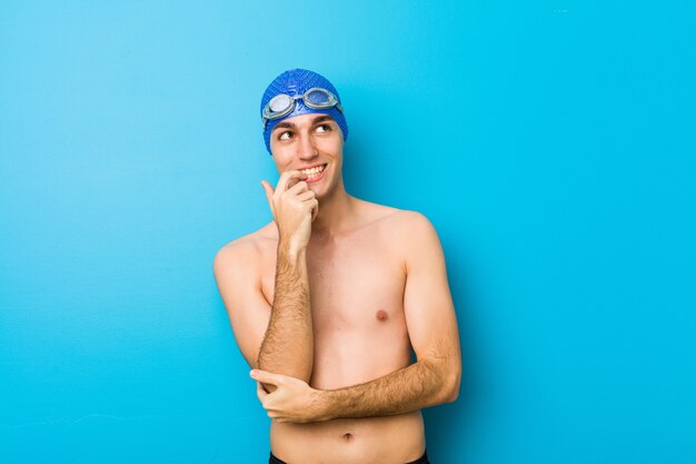 Young swimmer man relaxed thinking about something looking at a copy space.