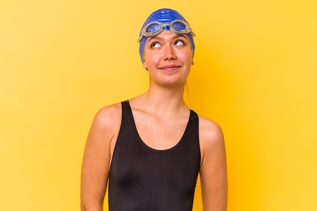 Donna venezuelana giovane nuotatore isolata sulla parete gialla che sogna di raggiungere obiettivi e scopi