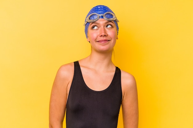 Young swimmer venezuelan woman isolated on yellow wall dreaming of achieving goals and purposes