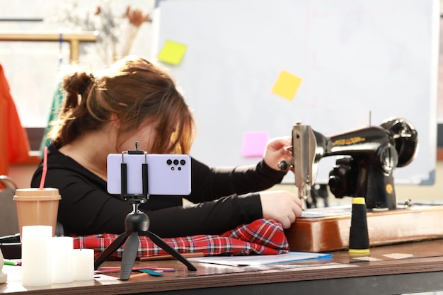 Young tailor sitting at the desk and using sewing machine