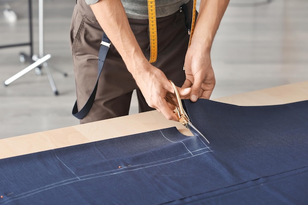 Young tailor working with textile in atelier