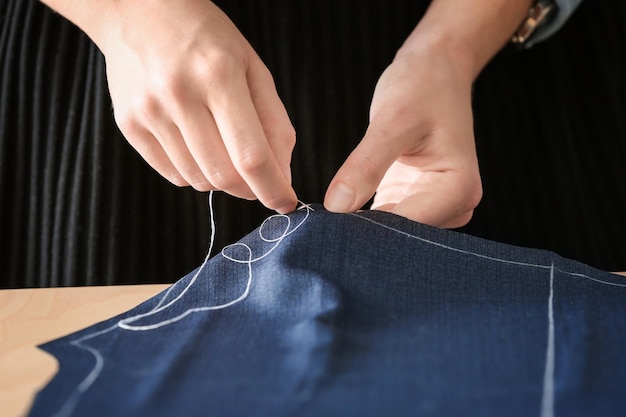 Young tailor working with textile closeup