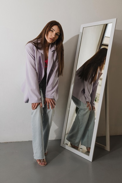 Young tanned girl holding her knees in stylish clothes