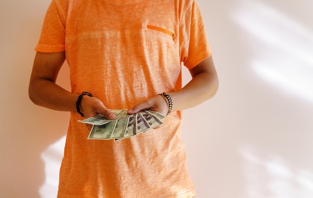 Молодой загорелый мужчина держит в руках деньги, доллары, пространство для копирования текста.