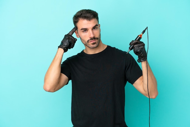 Young tattoo artist man isolated on blue background having doubts and thinking