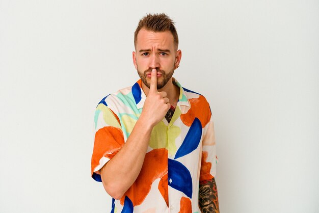 Young tattooed caucasian man isolated on white background thinking and looking up, being reflective, contemplating, having a fantasy.