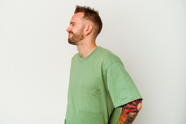 Young tattooed caucasian man isolated on white wall suffering a back pain.