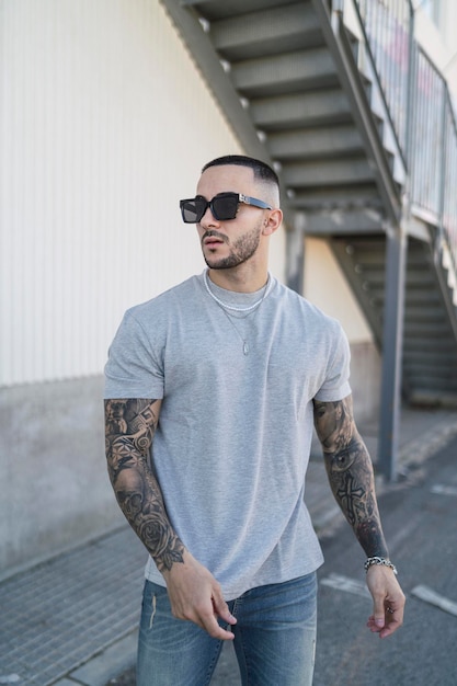 young tattooed man possing with urban wear in the street