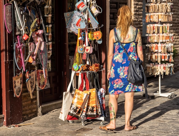 Young tattooed woman shopping in a souvenir shop in Toledo