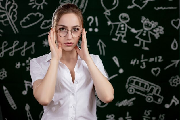 Young teacher is standing near blackboard in classroom