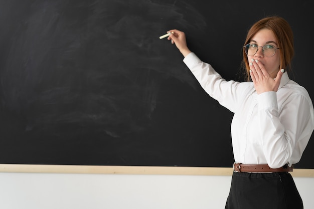 Young teacher is standing near the blackboard