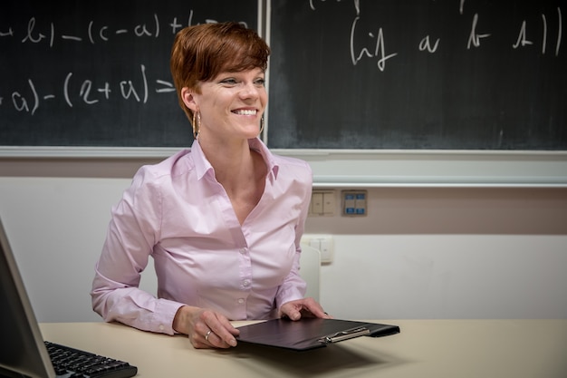 Young teacher lectures at the School of Mathematics, writes chalk on a blackboard