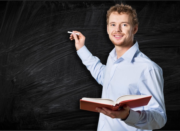 Young teacher near chalkboard in school classroom