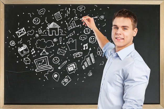 Young teacher near chalkboard in school classroom