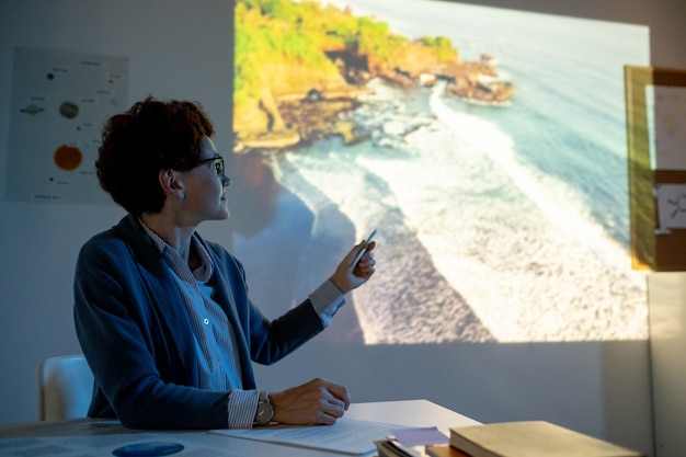 Young teacher pointing at coastline during video presentation
