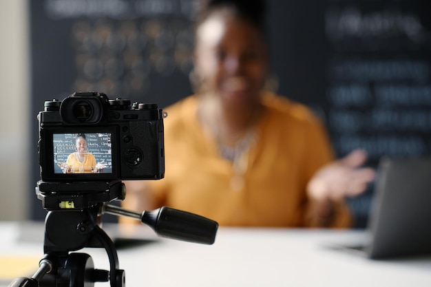 Photo young teacher recording her blog while sitting at table in front of digital camera