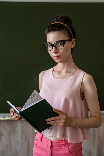 Young teacher standing near empty blackboard and explain new lesson