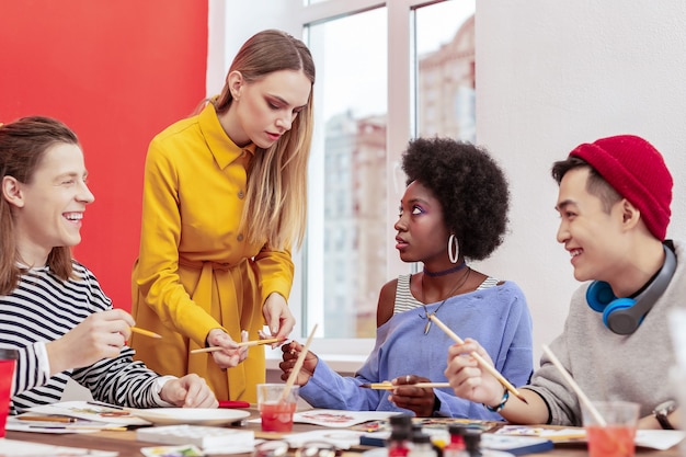 Young teacher. Three stylish good-looking students looking and listening to their young teacher