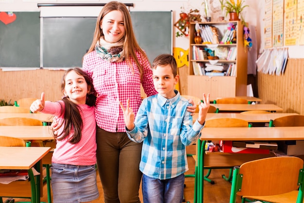 The young teacher with a schoolboy and schoolgirl stands in the middle of a class