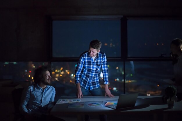 young team of business people in group, architect and engineer on construction site checking documents and business workflow using laptop computer in new startup office at night