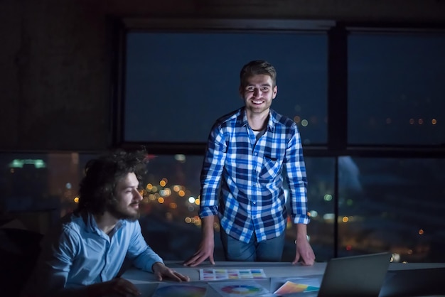 young team of business people in group, architect and engineer on construction site checking documents and business workflow using laptop computer in new startup office at night